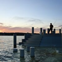 A person fishing at sunset in the Hudson River at Scenic Hudson's Long Dock Park.