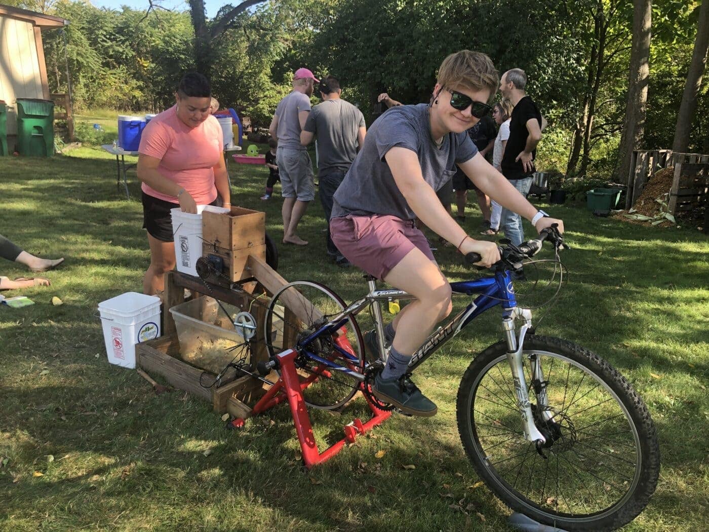 A person outdoors riding an apple-pressing bike.